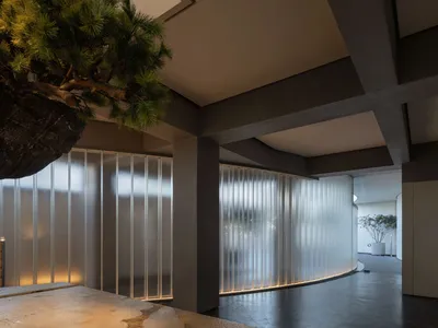 現代酒店大廳，特色為混凝土牆面與弧形玻璃牆，搭配照明燈光。