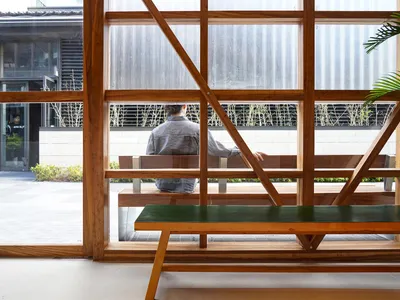 A modern restaurant bar with wooden furniture and green plants.