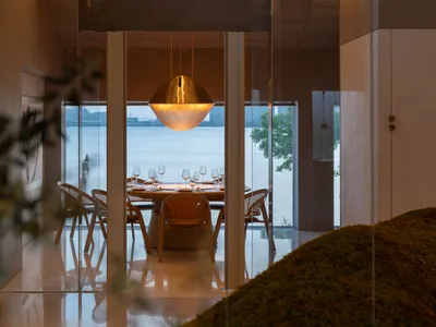 A modern elegant restaurant featuring metallic bronze lighting and minimalist concrete flooring.
