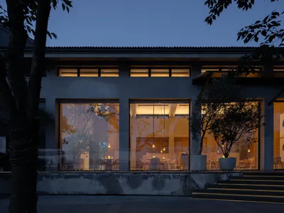 Modern restaurant exterior with concrete frame and glass windows at night