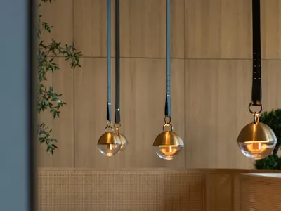 Modern restaurant dining room with wooden tables, chairs, and pendant lights.