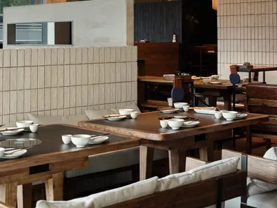 A modern restaurant interior with warm wooden elements, featuring clean lines and minimalist design.