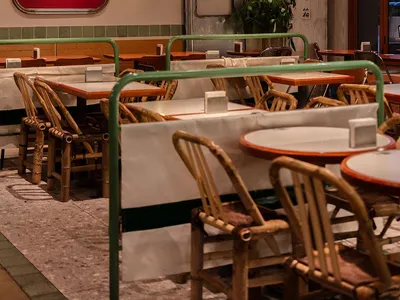 An industrial-themed restaurant interior with wooden furniture and a red sign.
