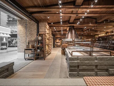 Interior view of an industrial-style restaurant featuring exposed brick walls, wooden beams, and stone accents.