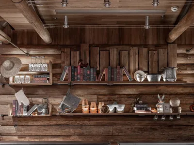 Industrial-style shelves in a restaurant setting, featuring rustic wooden walls and shelves adorned with books, jars, and dec
