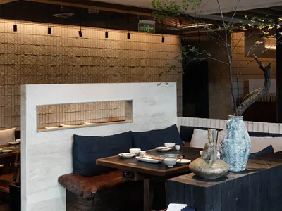 A modern restaurant interior with wood, concrete, and textile elements.