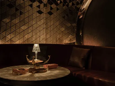 A modern restaurant interior featuring metallic walls and a round, metallic table with a lamp.
