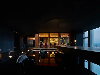 A dark and luxurious hotel suite featuring dark wood furniture and glass accents, creating a serene and sophisticated atmosph