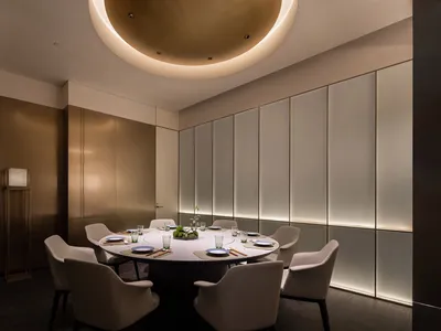Modern elegant restaurant dining room with circular table, chairs, and decorative elements.