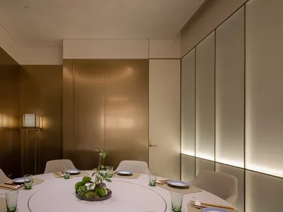 A modern, metallic-themed restaurant dining room with a circular table set for six, featuring a minimalist centerpiece and am
