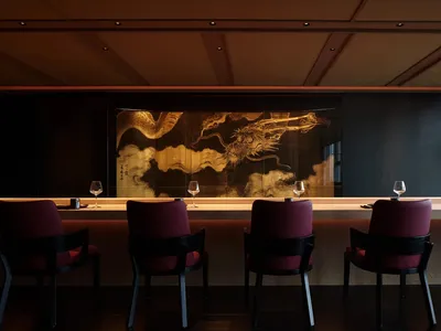 Modern restaurant bar with wooden tables, chairs, and a marble countertop.