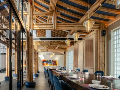 Modern restaurant interior with bamboo ceiling, glass walls, and wooden furniture.