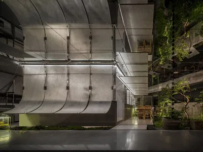 A sleek, modern restaurant interior featuring metallic and concrete materials.