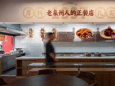 A modern restaurant food court counter featuring granite countertops and a menu displayed in the background.