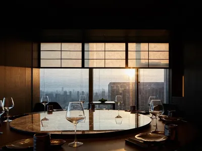Modern restaurant interior with glass walls and sunset view.