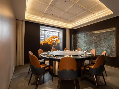 A modern interior design featuring contemporary furniture, a round dining table, and a decorative tree centerpiece.