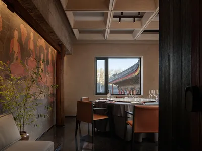 Modern, minimalist restaurant interior with concrete walls and a view through a window
