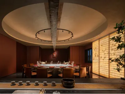 An elegant, modern restaurant interior with wooden elements and a circular ceiling light fixture.