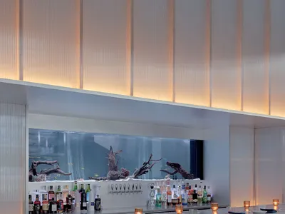 A sleek, modern restaurant bar featuring glass and marble surfaces.