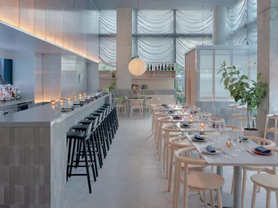 A modern restaurant interior featuring exposed concrete walls and wooden accents.