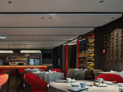 A modern restaurant interior featuring red leather furniture and white tablecloths.
