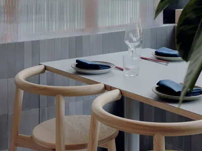 A modern restaurant interior with wooden tables and chairs.