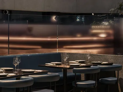 A modern restaurant interior featuring metallic lighting and concrete finishes.
