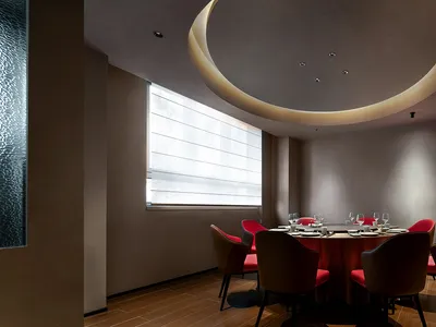 Modern dining room with concrete walls, red accent walls, and a round dining table.