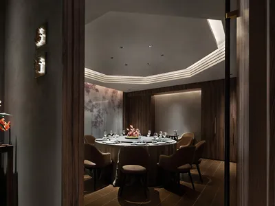A modern restaurant dining room with dark wood accents and a round table set for a meal.