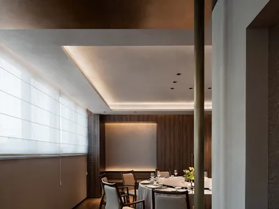 Modern restaurant interior with sleek, minimalist design features, including wooden paneling, leather seating, and glass elem