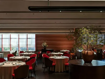 Modern restaurant with round tables, red chairs, and contemporary lighting fixtures.