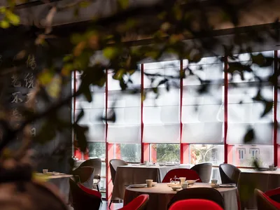 Modern restaurant interior with white blinds and white tablecloths.