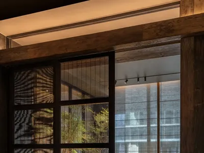 A modern restaurant interior with wooden tables, glass walls, and minimalist decor.