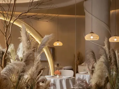 A modern restaurant interior featuring pampas grass and lighting.