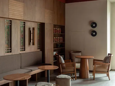 Modern restaurant interior with wooden furniture, leather seats, and concrete flooring.