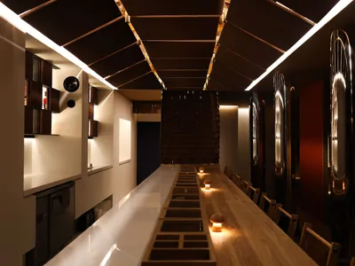 Wooden counter in a modern restaurant interior with illuminated elements and a sleek design.