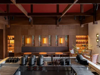 Industrial-style restaurant interior with wooden walls and seating, illuminated by warm lighting.