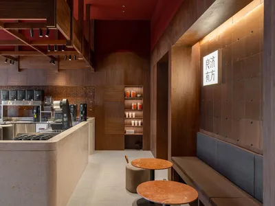 A modern restaurant bar with wooden and stone elements, illuminated by warm lights and featuring a sleek countertop with a se