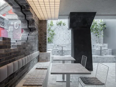 Modern restaurant interior with concrete walls and white tiled floors.