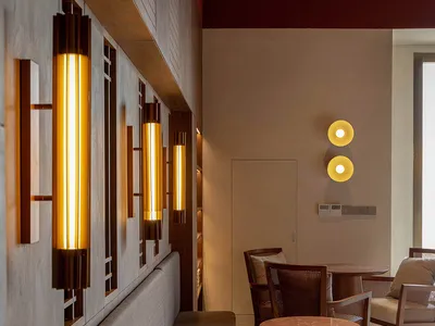 Modern restaurant interior featuring wooden seating and table arrangements with decorative lighting fixtures.