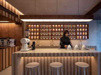 A coffee shop counter with a barista preparing coffee in the background.