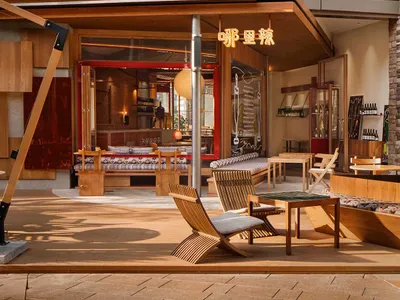 Outdoor patio of a modern restaurant with wooden furniture and structural elements.