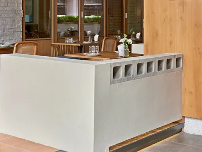 Interior design of a modern restaurant featuring a wall with a combination of concrete, wood, and brick materials.