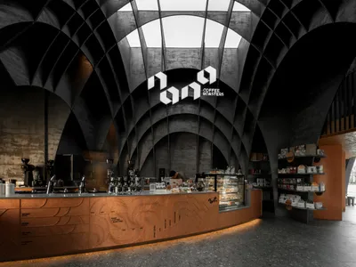 A modern, industrial-style coffee shop with a concrete counter featuring a logo for a coffee roasters brand below it.