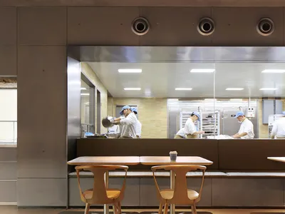 工業風餐廳廚房，混凝土地板與牆面，廚師在透明隔板後準備餐點