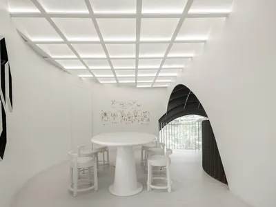 White minimalist interior design of a restaurant/cafe with a round white table, white stools, and framed black artwork on whi