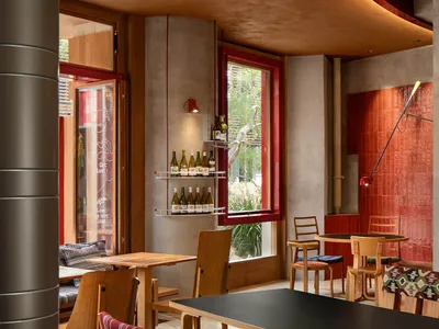 A modern café interior featuring a wooden counter with red accents and mixed materials.