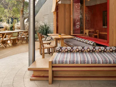 A restaurant exterior featuring industrial design elements with warm materials like wood, metal, and fabric.