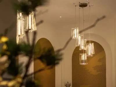 A modern restaurant interior with glass lighting fixtures hanging from the ceiling, and tables set for dining.
