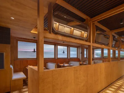 Contemporary restaurant interior featuring modern wooden design elements, including booth seating and large windows allowing